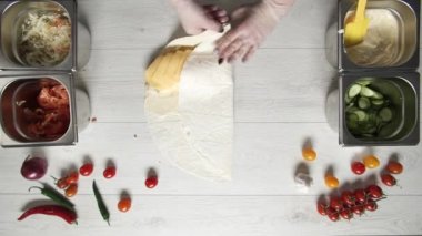 Şefin beyaz eldivenli üst görüntüsü kebapçı kebabı pide veya lavda. Tavuk, patates kızartması, peynir ve sebzeli shawarma pişiriyorum.