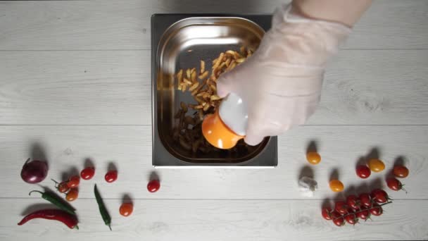 Шеф-повар в перчатках намазывает соль на горячую и вкусную картошку фри — стоковое видео
