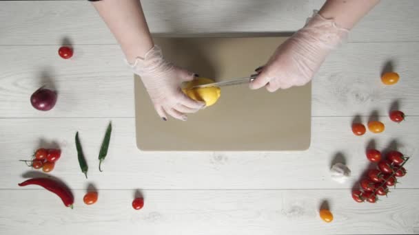 Šéfkuchař v rukavicích krájí citrón na prkně. Ručně krájený citron na sekání prkna detailu. Šťavnatý citron nakrájený na plátky. Ostrý kuchařský nůž krájí citrusové plody. — Stock video