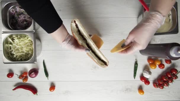 Vista superior de las manos de chef profesional en guantes haciendo shawarma en sándwich en pan. Chef en guantes pone queso en sándwich — Vídeos de Stock