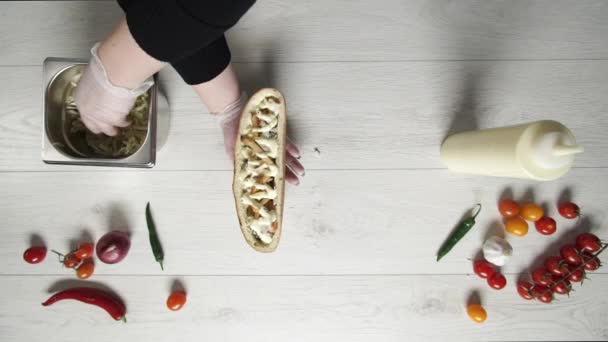 パンにサンドイッチにシャワルマを作る手袋でプロのシェフの手のトップビュー。シェフがキャベツをサンドイッチに入れる — ストック動画