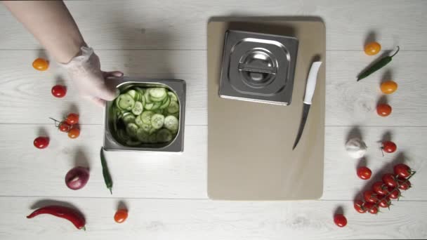 Chef ferme le récipient en métal avec des concombres coupés 