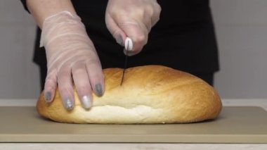 Şef plastik kesim tahtasıyla taze ekmek kesiyor..