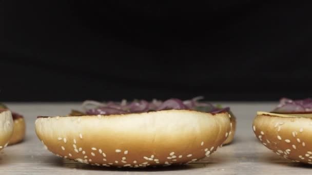 Vista superior de chef profesional cocina una deliciosa hamburguesas en el restaurante de comida rápida. La cocinera en guantes pone queso en tres hamburguesas — Vídeo de stock