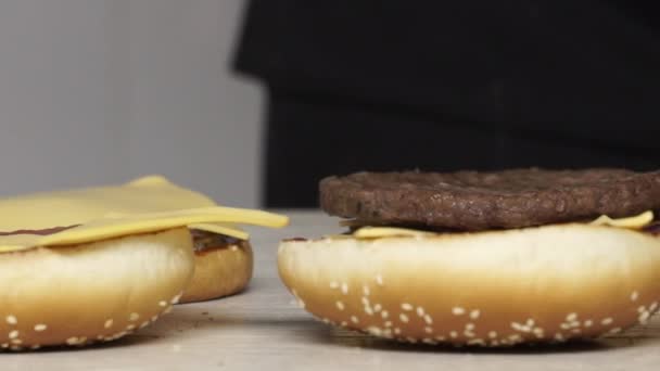 Profesyonel aşçı üç farklı yemek yapar. Fast food restoranında lezzetli bir burger. Eldivenli kadın aşçı hamburgerin üstüne ızgara tavuk koymuş. — Stok video