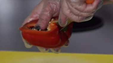 Şefin yakın çekimleri, Çin dolma biberini plastik tahta üzerinde kesiyor.