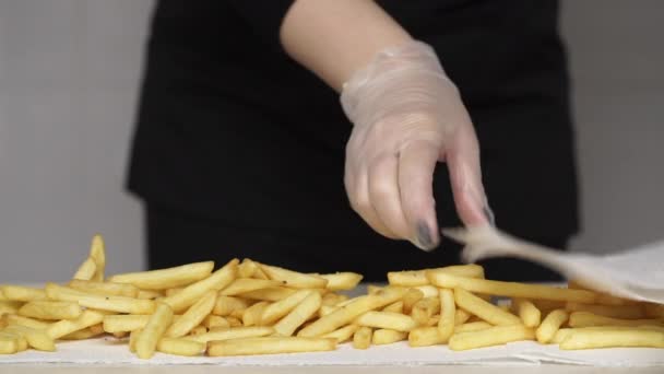 Шеф-повар в перчатках снимает жир с горячей и вкусной картошки фри — стоковое видео