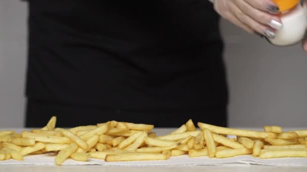 Chef em luvas coloca sal em batatas fritas quentes e deliciosas — Vídeo de Stock