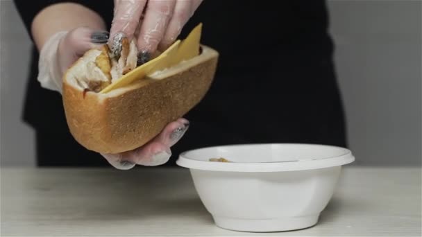 パンにサンドイッチにシャワルマを作る手袋のプロのシェフの手。手袋のシェフはサンドイッチにフライドポテトと鶏の肉を置きます — ストック動画