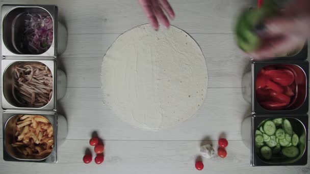 厨师手戴白色手套的头像将黄瓜放在意大利面或意大利面中的烤面包沙瓦玛上。沙瓦玛，鸡肉，薯条，奶酪和蔬菜 — 图库视频影像