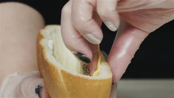 Close-up van de handen van professionele chef-kok in handschoenen het maken van shawarma op sandwich in brood. Chef in handschoenen doet kaas in sandwich — Stockvideo