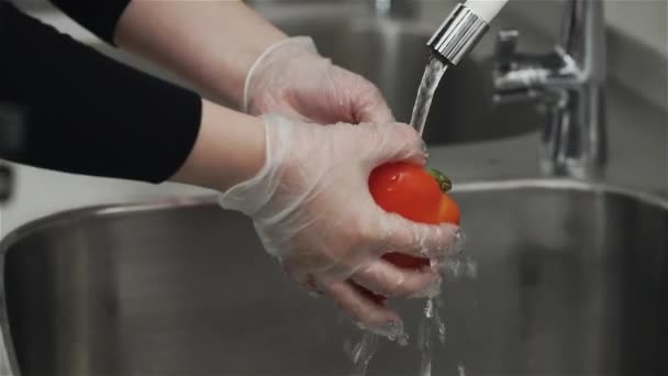 Lava la frutta. Donna sopra il lavandino sotto l'acqua lava peperone rosso — Video Stock