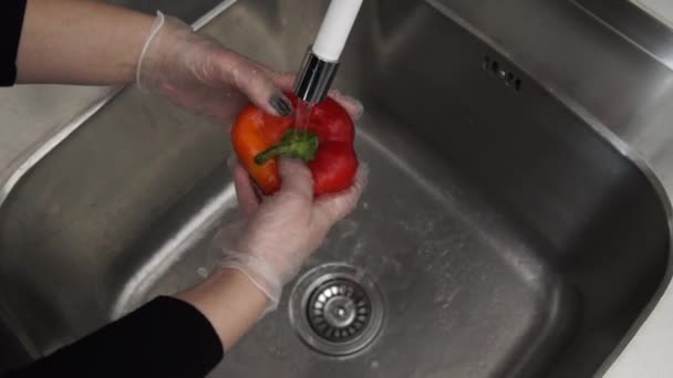 Lava la frutta. Donna sopra il lavandino sotto l'acqua lava peperone rosso — Video Stock