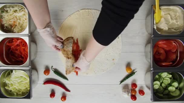 Bovenaanzicht van chef-kok handen in witte handschoenen zet rundvlees cutlet op doner kebab shawarma in pita of lavash. Shawarma met kipfilet, paprika, kaas en groente — Stockvideo