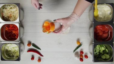 Profesyonel şef fast food restoranında lezzetli bir hamburger pişiriyor. Eldivenli kadın aşçı burgerin üzerine tuz döküyor.