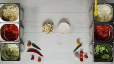 Profesyonel şef fast food restoranında lezzetli bir hamburger pişiriyor. Eldivenli kadın aşçı hamburgerin üstüne peynir koyar.