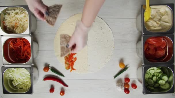 Vista dall'alto di mani di chef in guanti bianchi mette costoletta di manzo su doner kebab shawarma in pita o lavash. Shawarma con costoletta di manzo, papaveri, formaggio e verdure — Video Stock