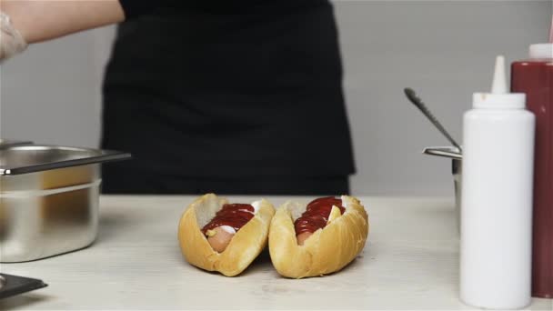 Chef mains dans les gants cuisine un hot dog, saucisse dans la pâte . — Video
