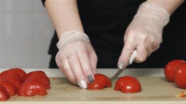 Şef domatesleri plastik tahtada keser.