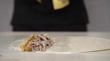 Şefin beyaz eldivenli elleri, kebap ya da lavaşın içine peynir koyar. Tavuk, patates kızartması, peynir ve sebzeli shawarma.