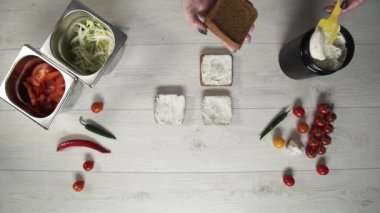 Profesyonel şefin en iyi görüntüsü fast food restoranında lezzetli bir hamburger pişirir. Eldivenli kadın aşçı hamburgerler için şiş ekmek koyuyor.