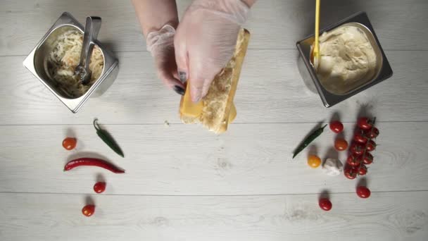 A vista superior do chef profissional cozinha um delicioso sanduíche no restaurante fast food. Chef feminino em luvas coloca queijo em sanduíche — Vídeo de Stock