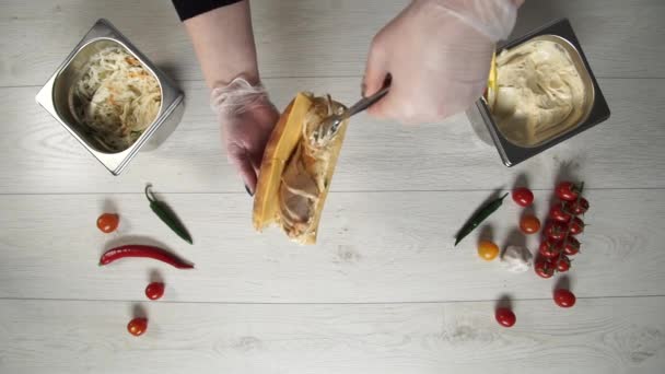 Vista superior de chef profesional cocina un delicioso sándwich en el restaurante de comida rápida. Cocinera en guantes pone carne de cerdo en sándwich — Vídeo de stock