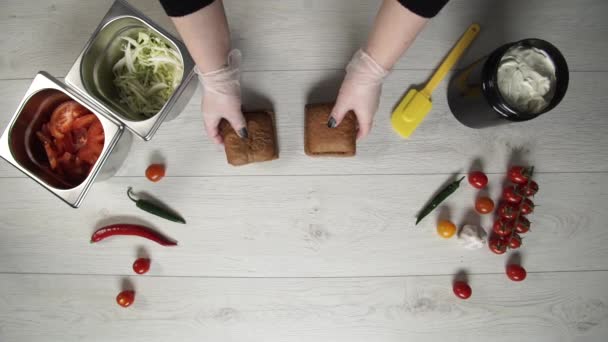 Der Chefkoch kocht im Fast-Food-Restaurant einen leckeren Burger. Köchin in Handschuhen öffnet zwei Bärte für Burger auf dem Tisch — Stockvideo