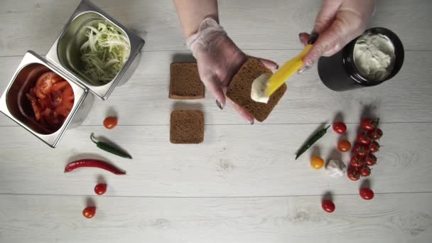 Vista superior de chef profesional cocina una deliciosa hamburguesas en el restaurante de comida rápida. Mujer chef en guantes pone souse en panes tostados para hamburguesas — Vídeo de stock