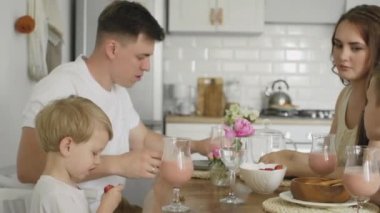 Mutlu bir ailenin sabahları mutfak masasında oturup birlikte kahvaltı etmesi ve eğlenmesi.