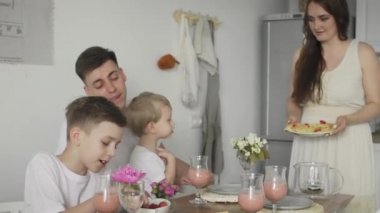 Mutlu bir ailenin sabahları mutfak masasında oturup kahvaltıda waffle yemesi.