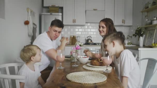 Gelukkig gezin zitten rond keukentafel in de ochtend samen ontbijten en plezier hebben — Stockvideo