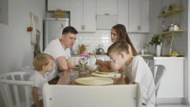 Glad familj med barn runt köksbordet äter frukost — Stockvideo