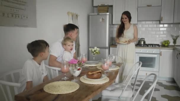 Счастливая семья, сидящая по утрам за кухонным столом и завтракающая вафлями — стоковое видео