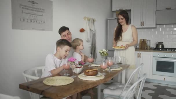Счастливая семья, сидящая по утрам за кухонным столом и завтракающая вафлями — стоковое видео