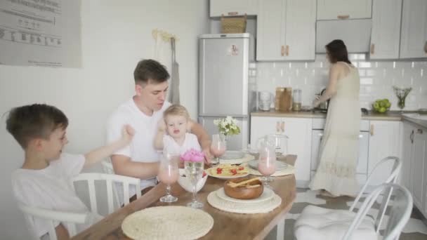 Familie mit Teenagerkindern frühstückt in einer weißen Küche — Stockvideo