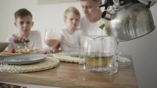 Familie ontbijten. Moeder gieten een heet water naar thee waterkoker — Stockvideo