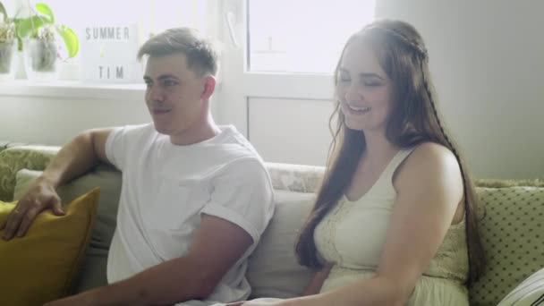 Dobře vypadající bělošská rodina matky, otce a dvou synů sedících na pohovce v obývacím pokoji — Stock video