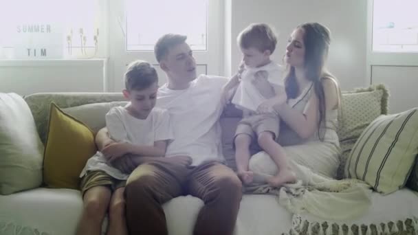 Przystojny biały rodziny matki, ojca i dwóch synów siedzi na kanapie w salonie — Wideo stockowe