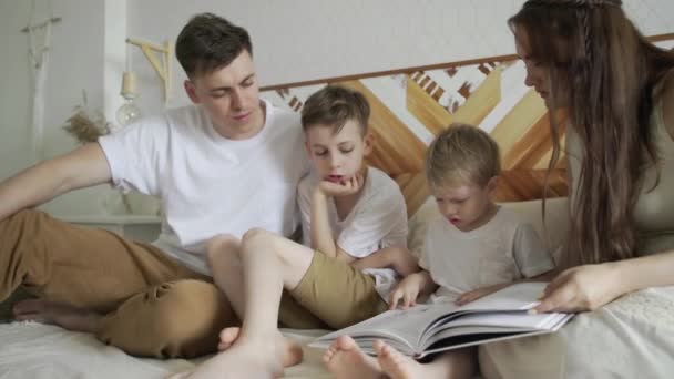 Primer plano de la familia mamá, papá y dos hermanos leen libros sentados en el sofá. Tiempo de lectura familiar . — Vídeos de Stock