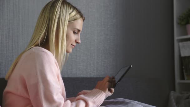 Primer plano de la mujer feliz jugando el juego en la tableta sentado en un sofá en casa — Vídeo de stock