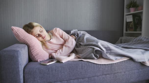 Μια νεαρή όμορφη γυναίκα ξύπνησε από ένα τηλεφώνημα. Γυναίκα κοιμάται στον καναπέ στο σαλόνι — Αρχείο Βίντεο