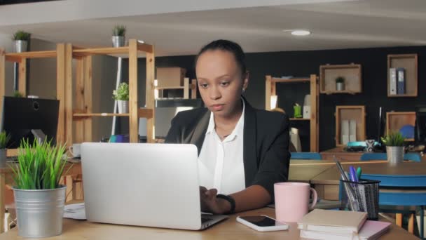 Νεαρή Αφροαμερικανή δακτυλογραφεί σε φορητό υπολογιστή στο γραφείο — Αρχείο Βίντεο