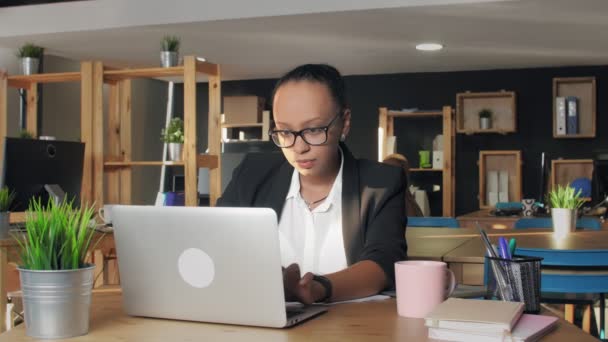 Dissatisfied african american woman in glasses types on notebook and then closes it — Stock Video