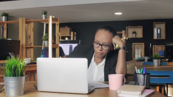 Aburrida mujer afroamericana sintiéndose soñolienta mientras está sentada en la oficina — Vídeo de stock