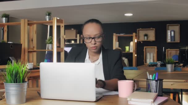 Mujer afroamericana joven escribiendo en el portátil y bebiendo un café — Vídeo de stock