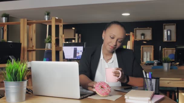 Genç Afro-Amerikan kadın ofiste öğle yemeği yiyor. Kadın donut yemek istemiyor, sebze yemeye karar verdi. — Stok video