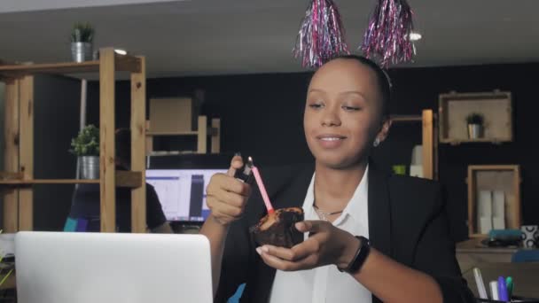 Κοντινό πλάνο της χαρούμενης Αφροαμερικανής μάνατζερ που γιορτάζει τα γενέθλια και κάνει μια ευχή στο γραφείο. — Αρχείο Βίντεο