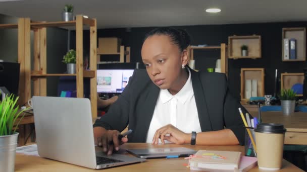 Afrikai amerikai nő tervező dolgozik egy laptop egy grafikus tabletta. — Stock videók