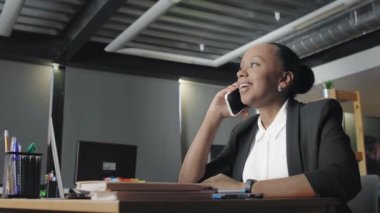 İş yerinde telefonla konuşan Afrikalı Amerikalı genç bir kadının yan görüntüsü.